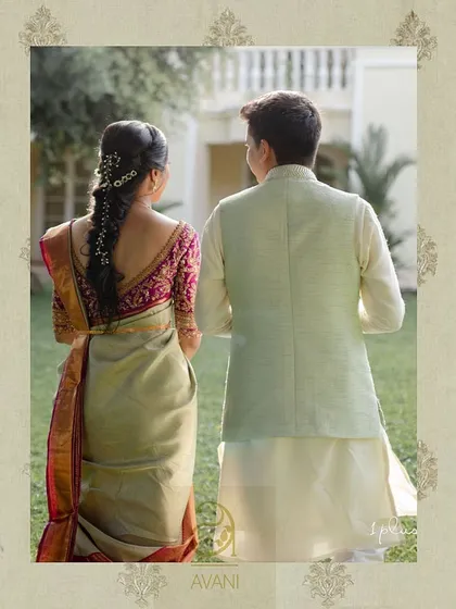 A back view of the couple, showcasing the bride's magenta blouse with its intricate back embroidery and elegant design.