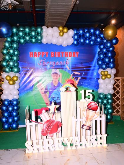 This cricket-themed birthday decoration includes a full balloon arch, a personalized photo backdrop, and light-up marquee letters spelling out the name, creating a complete party stage.