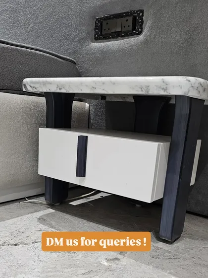 A close-up of the marble-topped side table, showing the contrast between the polished stone, the white drawer, and the dark legs and handle.