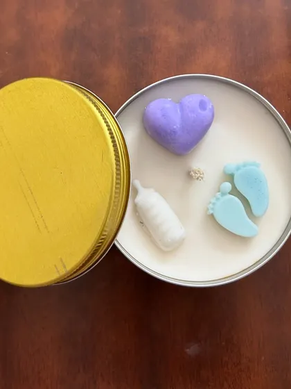 We can add these cute baby-themed wax shapes to the top of our candles. This one has a heart, a milk bottle, and tiny baby feet.