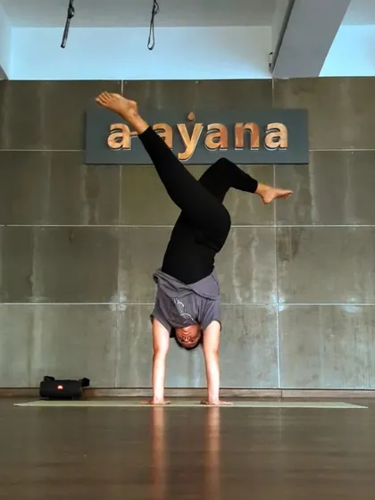 "Let it hurt, then let it go." An instructor holds a challenging handstand variation, embodying the philosophy of moving through discomfort to find release.