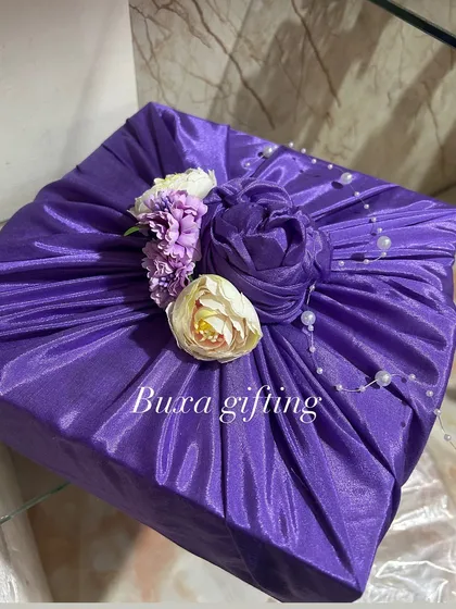 The presentation is just as important as the gift itself. I love using unique wrapping techniques, like this beautiful purple satin cloth wrap, adorned with faux flowers and pearls, to make the unboxing experience feel truly luxurious and special for a bride-to-be.