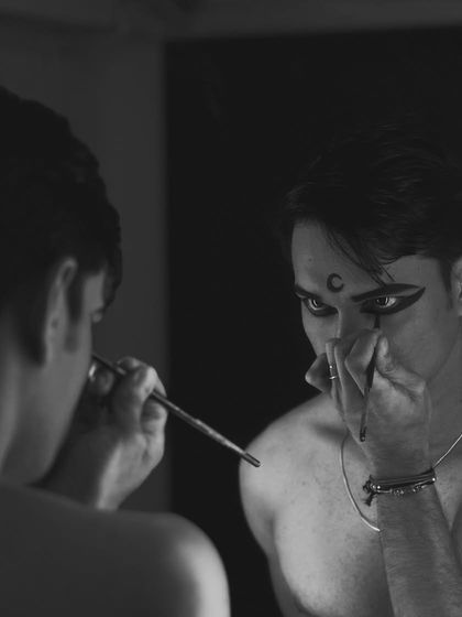 Another black and white shot of the makeup process. The mirror reflects the transformation from person to performer.