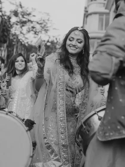 A beautiful black and white shot of a guest dancing with the dhol players, capturing the timeless joy of a wedding baraat.