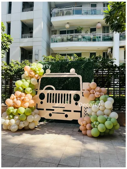 An outdoor safari jeep photo booth, decorated with balloon clusters.