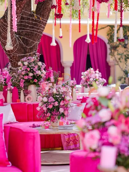 A closer look at the lounge seating, where fuchsia sofas are surrounded by a sea of pink and lavender floral arrangements. We used books and other small props to add layers and personality to the coffee tables.