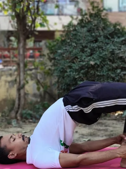 An instructor in Setu Bandhasana (Bridge Pose). This pose stimulates the abdominal organs, which can help improve digestion and relieve symptoms of abdominal pain.
