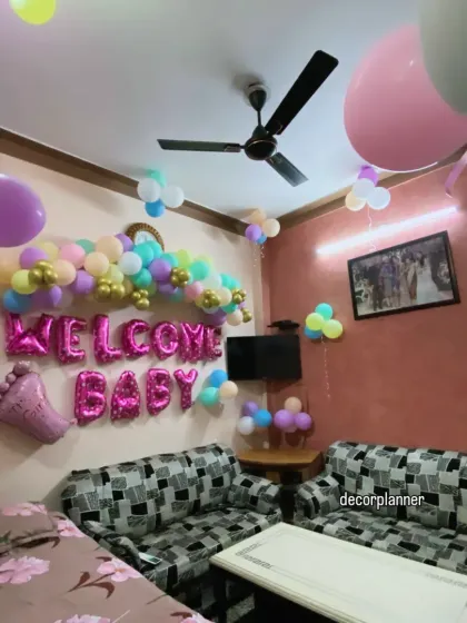 A cheerful and colorful "Welcome Baby" setup at Nani's home. The pastel balloon garland and bright pink foil letters create a fun and loving atmosphere to celebrate the baby's arrival.