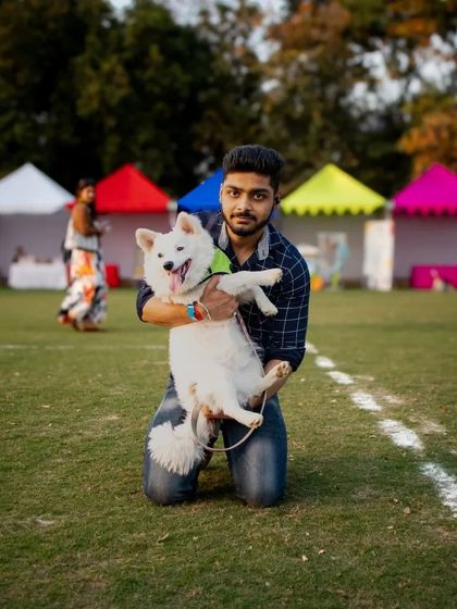 A pet parent holding his happy Pomeranian against the backdrop of colorful event tents. I take care of all the background logistics so you can focus on having fun.
