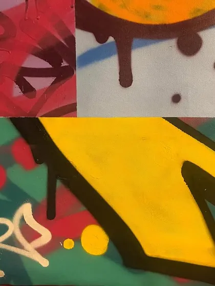 A macro shot of a canvas, focusing on the textures and layering of different spray paint techniques. You can see the drips, fades, and sharp outlines up close.
