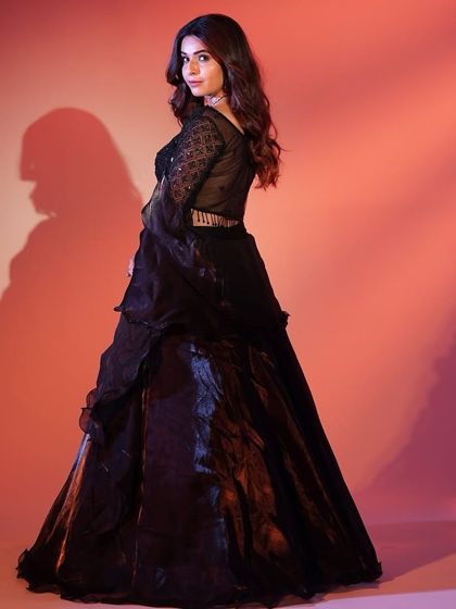 The back of this black lehenga shows off its elegant silhouette and the way the flared sleeves add a touch of drama.