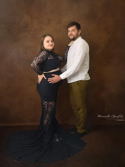 A beautiful portrait showcasing the baby bump. The partner's hands gently cradle the bump, a classic pose that emphasizes their shared journey.