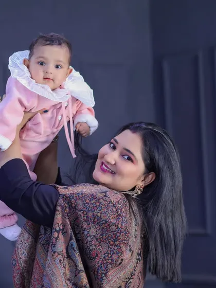 A proud mother holding her baby high. The baby's adorable pink outfit and direct gaze at the camera make this a captivating mother-child portrait.