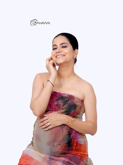 A happy and candid studio portrait of a mother-to-be in a colorful abstract dress.