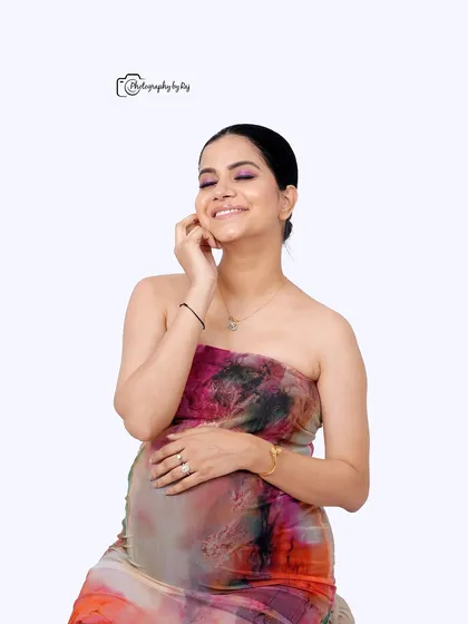 A happy and candid studio portrait of a mother-to-be in a colorful abstract dress.