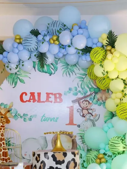 A close-up of the custom backdrop and balloon arch for Caleb's party, featuring soft pastel colors.