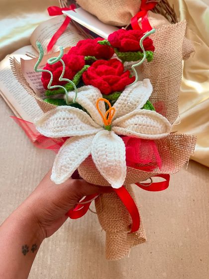 A hand holding the red rose and white lily bouquet, showing off the paw print tattoo that is a tribute to my original inspiration, Buddy.