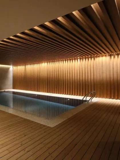 Another view of the indoor pool, showing how the warm lighting on the wood-clad wall creates a stunning reflection on the water.