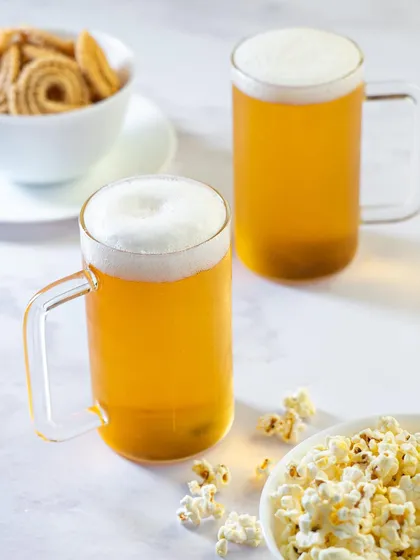 Showing product versatility. Here, the Borosil mugs are paired with different snacks like popcorn and chakli, suggesting they are perfect for any kind of casual get-together.