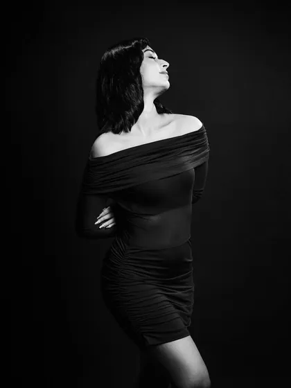 A classic black and white portrait. The off-the-shoulder dress and the elegant pose create a timeless and sophisticated look, essential for any model's book.