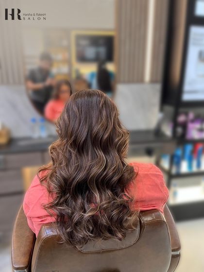 The after shot of a hair glow-up, featuring soft brown balayage on long hair, styled into gentle waves.