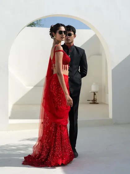 On-trend pieces that are easy on the pocket. This couple is styled in a modern red sequin saree and a classic black bandhgala, proving you don't have to spend a fortune to look amazing together.