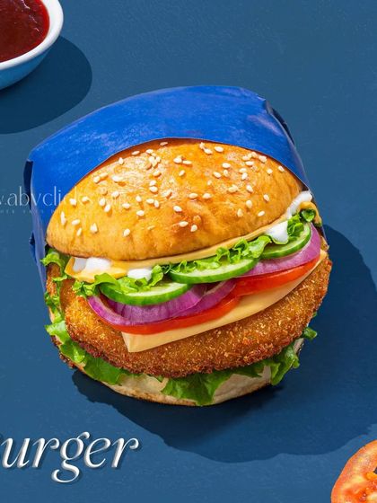 A loaded vegetable burger with a crispy patty, fresh lettuce, cucumber, and onion, shot for a Pepsi campaign.