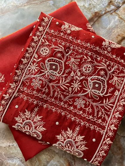 A folded view of the kurta, emphasizing the rich red color and the white threadwork.