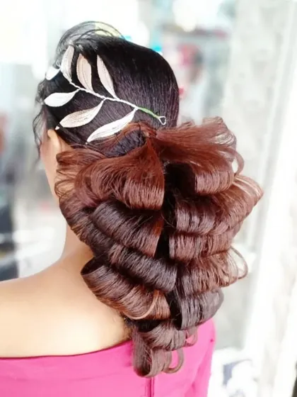 A creative ponytail style with dramatic, structured curls and a sleek silver accessory. This is an example of an advanced, high fashion hairstyle for editorial or runway work.