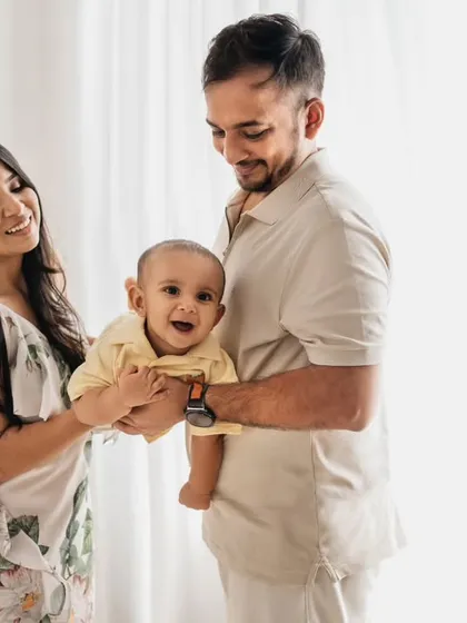 A lovely family of three, smiling together. This photo was taken during a first birthday session, showing how we can easily mix family portraits into milestone shoots.