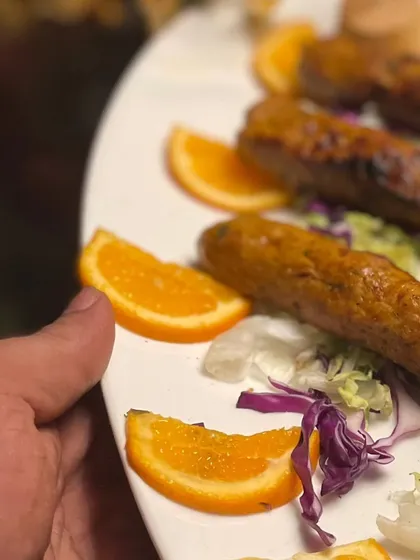 A platter of seekh kebabs being served, garnished with fresh orange slices for a hint of citrus that complements the smoky meat.