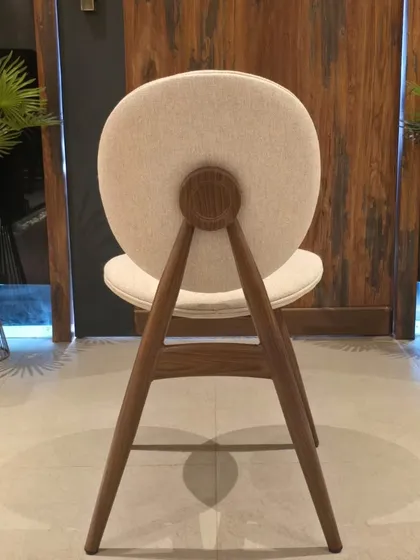 The back view of this dining chair highlights the unique wooden-finish metal frame and the circular cushioned back.