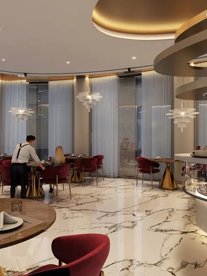 A wider view of the café at the Alibaug clubhouse, featuring rich red velvet chairs and marble-topped tables. The design creates a sumptuous and sophisticated atmosphere, perfect for escaping the city.