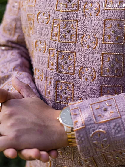 A close-up of a client's mauve sherwani, highlighting the intricate geometric embroidery in gold thread.