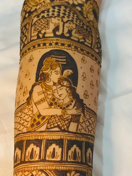 A close-up of a Shiva and Parvati portrait on the forearm, capturing a tender moment. This is a popular and meaningful element for bridal designs.