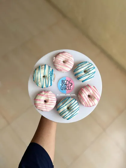 Pink and blue donuts, drizzled with white chocolate, are a sweet addition to any baby shower dessert spread.
