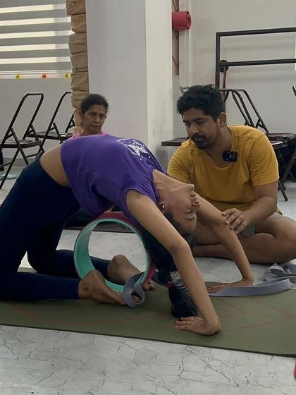 Using a yoga wheel to support a student in a deep backbend. Props are our best friends in yoga, helping us to explore poses that might otherwise seem impossible.