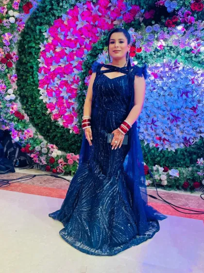 A client ready for her reception in a shimmering navy blue mermaid gown. The feathered shoulder detail and attached cape add a touch of modern glamour.