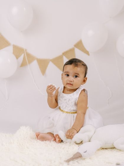 A simple and sweet portrait of a six-month-old girl in a white dress, ready for her milestone session.