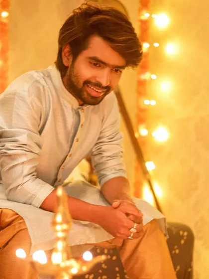 A candid, smiling shot. The warm glow from the diya in the foreground adds a beautiful touch to this festive portrait.