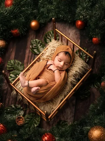 A sleeping newborn nestled in a tiny bed, surrounded by a festive wreath of pine and ornaments. This artistic shot is a beautiful way to celebrate your baby's first Christmas.