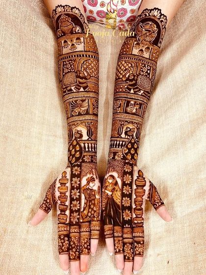 A beautiful bridal mehendi with bride and groom portraits on the palms, surrounded by lamps and other auspicious symbols.