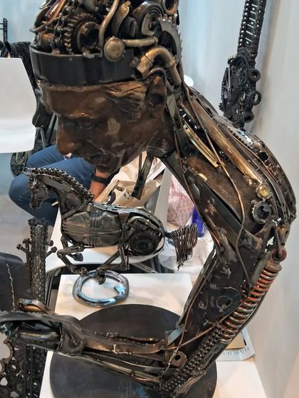 A metal sculpture of a person reading, with every detail crafted from mechanical parts and scrap metal.