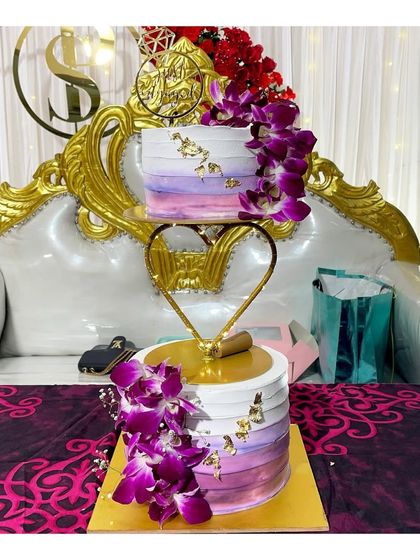 A beautiful 3kg engagement cake with a heart spacer, decorated with purple orchids and gold leaf. This cake was set up on a royal golden throne for the couple.