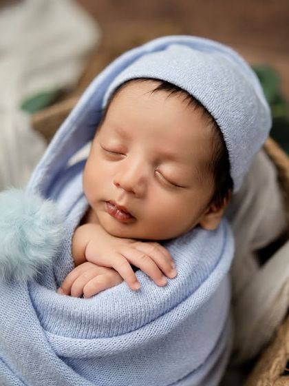 A close-up on the baby's face, highlighting the cute pom-pom on his sleepy hat and his perfectly peaceful expression.