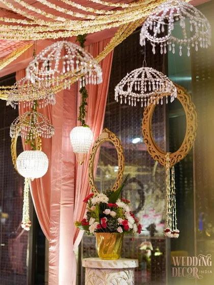A decorative corner featuring hanging crystal umbrellas, ornate mirrors, and floral arrangements. These elements come together to create a whimsical and glamorous atmosphere.