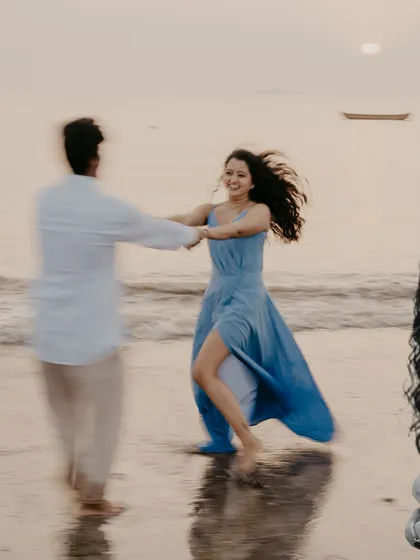 A joyful, motion-filled photo of the couple dancing on the sand at sunset, capturing pure happiness.