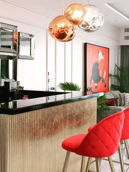 A full view of the bar setup, with its striking red stools, metallic fluted base, and a large piece of art in the background. It’s a space designed for lively conversations and making memories.