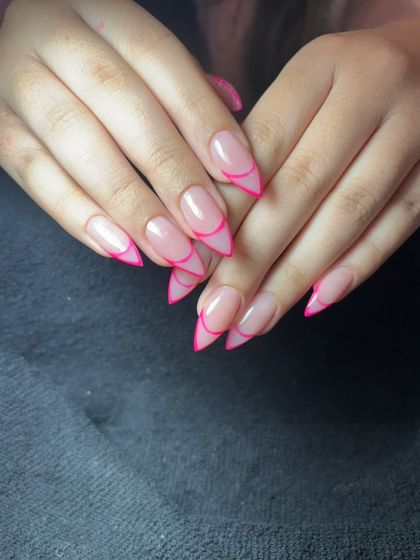 A neon pink outline French on sharp stiletto nails. This is a bold and trendy way to wear a classic.