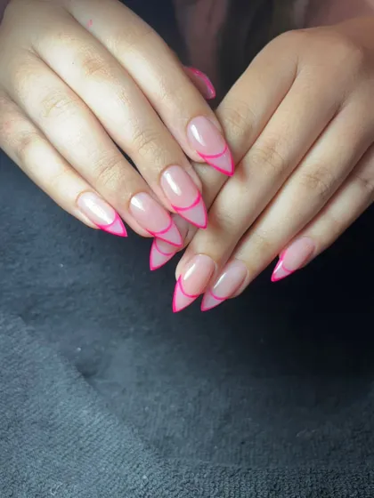 A bold and graphic take on the French manicure. This design features sharp, pointed stiletto nails with a neon pink outline instead of a traditional tip.